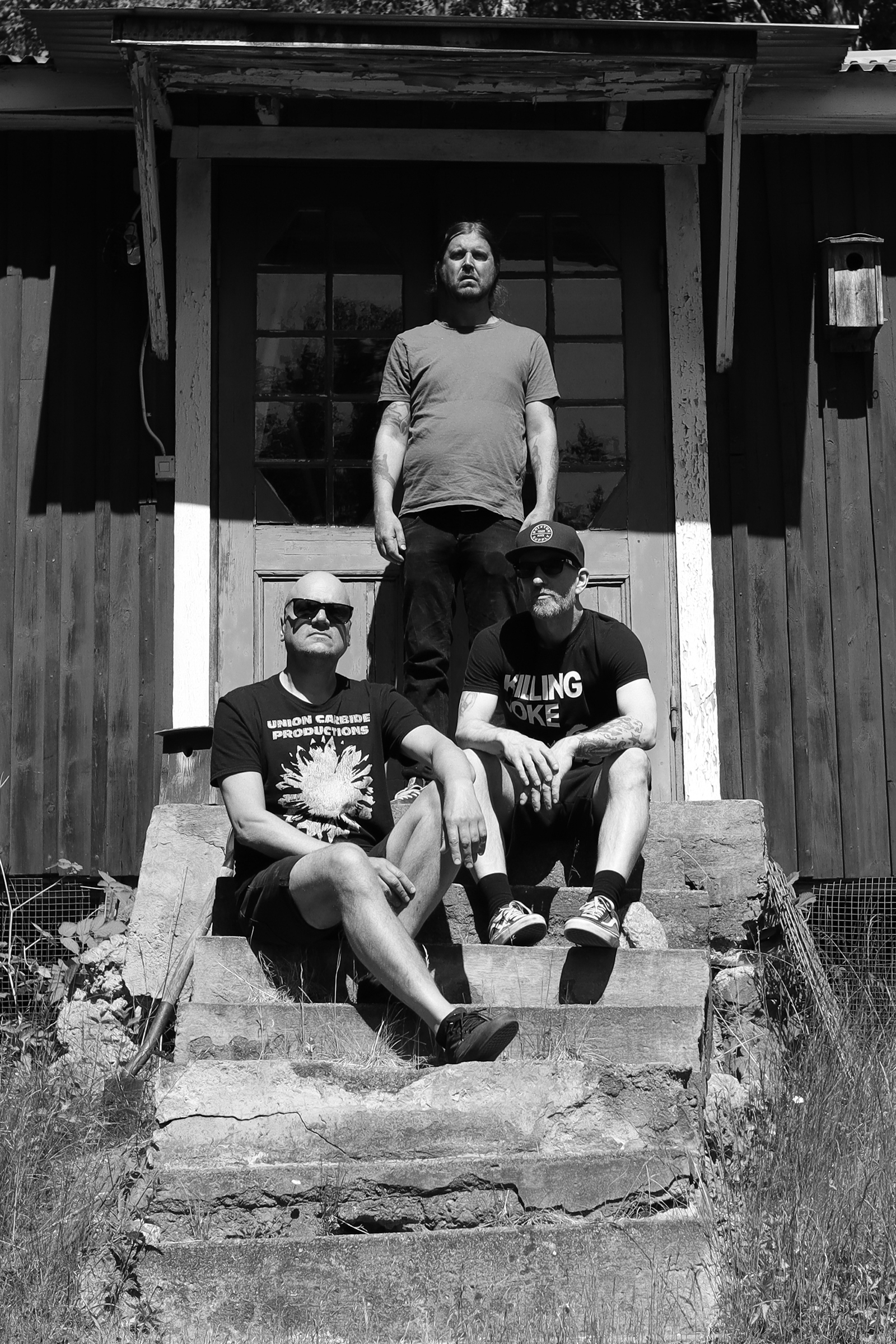 Vertical close-up photo of Haystack at Studio Underjord in Finspång, Sweden: Ulf, Jonas, and Patrik, with a distinct shadow on the wall behind them, captured by Joona Hassinen.