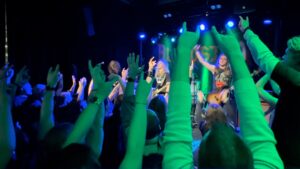 BLOODSTAIN live at The Kaliber Room in Uppsala, Sweden on 15 January 2026, seen through raised arms and “horns” from the crowd.